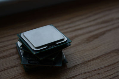 Close-up of multiple computer CPUs stacked on a wooden surface, showcasing technology components.