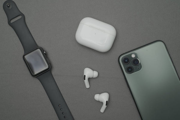 Flat lay of smartwatch, smartphone, and wireless earbuds on a gray background.