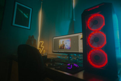 Atmospheric photo of a gaming setup with a glowing PC case and monitor displaying content editing software.