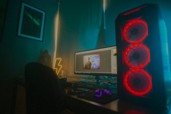 Atmospheric photo of a gaming setup with a glowing PC case and monitor displaying content editing software.