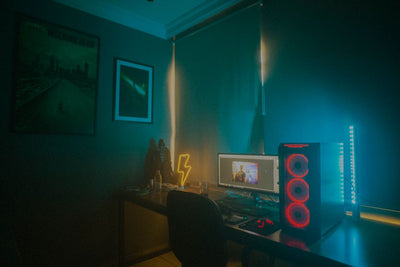A dimly lit minimalist gaming setup featuring a desktop PC and neon lights.