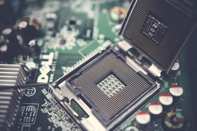 Detailed close-up shot of a computer motherboard featuring an open CPU socket and electronic components.