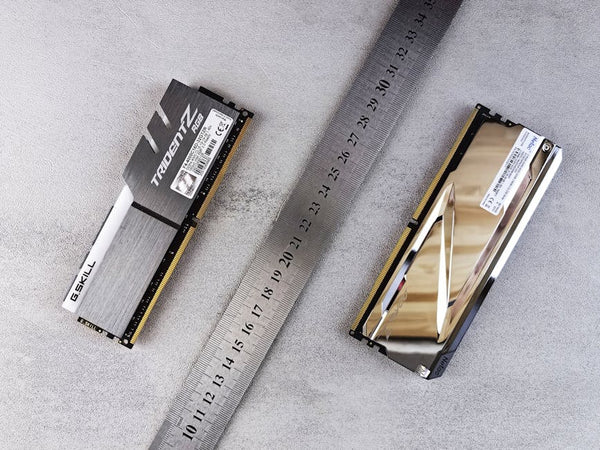 Close-up of computer memory modules and metal ruler placed on a textured gray surface.