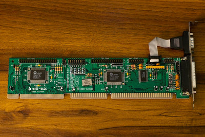 Close-up of a vintage computer circuit board showcasing intricate electronic details on a wooden surface.