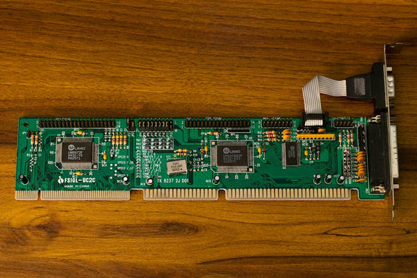 Close-up of a vintage computer circuit board showcasing intricate electronic details on a wooden surface.