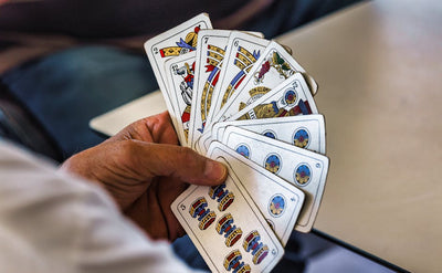Close-up of a hand holding a fan of traditional Briscola playing cards.
