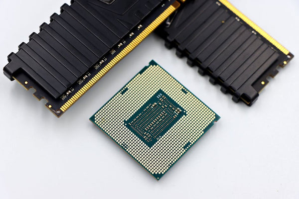 A CPU and RAM sticks displayed on a white surface, showcasing computer hardware components.