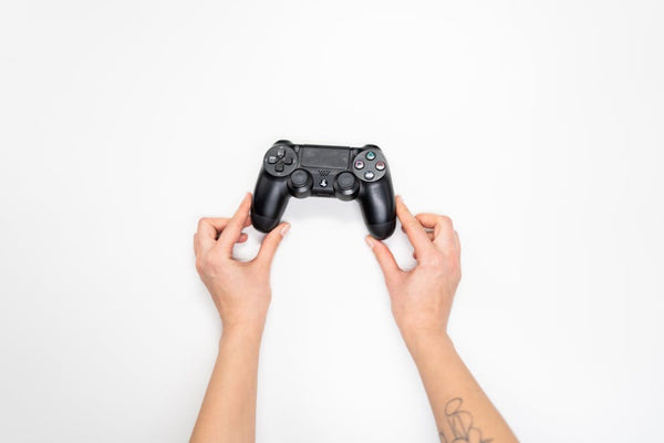 Top view of hands holding a black gaming controller against a white background.
