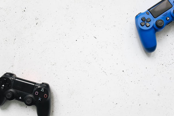 Top view of black and blue game controllers on a white surface.