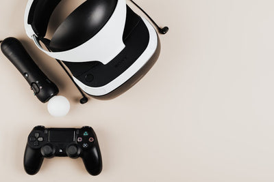 High-angle view of gaming controllers and VR headset on beige surface, showcasing modern technology.