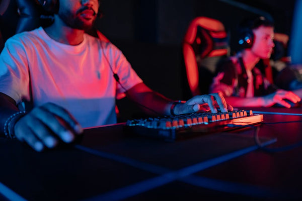 Two focused gamers in a neon-lit arena, wearing headphones and gaming intensely.