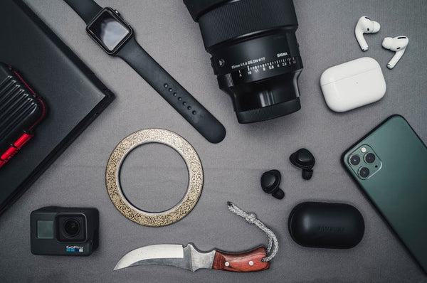 Flat lay of tech gadgets and personal accessories including camera and smartwatch.