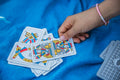 A hand picks a card from a Spanish deck on a blue blanket, showcasing traditional card game moments.