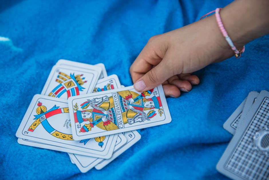 A hand picks a card from a Spanish deck on a blue blanket, showcasing traditional card game moments.