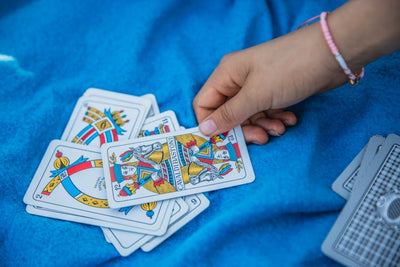 A hand picks a card from a Spanish deck on a blue blanket, showcasing traditional card game moments.
