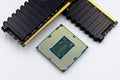 A CPU and RAM sticks displayed on a white surface, showcasing computer hardware components.