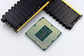 A CPU and RAM sticks displayed on a white surface, showcasing computer hardware components.