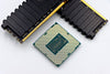 A CPU and RAM sticks displayed on a white surface, showcasing computer hardware components.