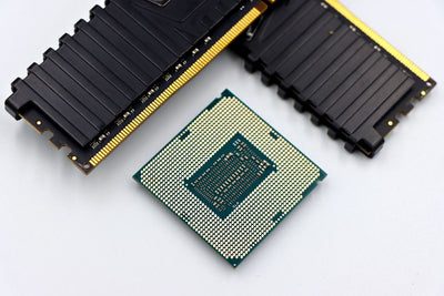A CPU and RAM sticks displayed on a white surface, showcasing computer hardware components.