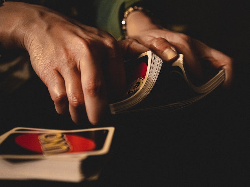 A dramatic close-up of hands shuffling Uno cards during a game night indoors.