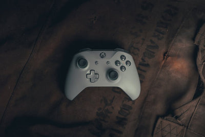 Top view of a gaming controller on rustic fabric, evoking a vintage gaming vibe.