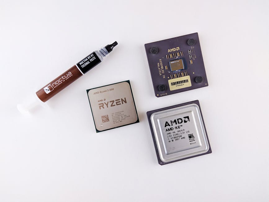 High-angle view of AMD processors and Noctua thermal paste on a white surface.