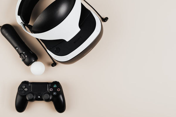 High-angle view of gaming controllers and VR headset on beige surface, showcasing modern technology.