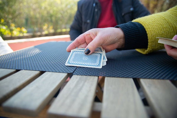 A close-up view of hands playing with playing cards outdoors on a sunny day.
