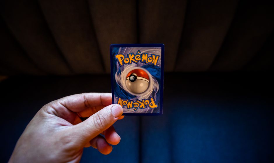 Crop unrecognizable person demonstrating collectible card dedicated to fictional creatures on dark background