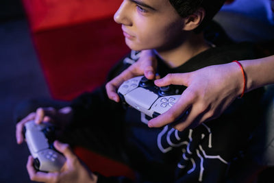 Close-up of teenagers playing video games together using modern game controllers.