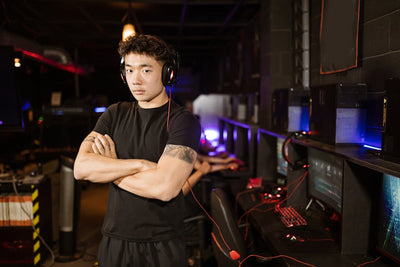 A confident gamer stands in a modern eSports arena, showcasing the gaming environment.