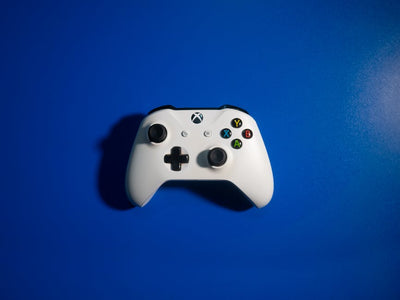 White wireless game controller on a vibrant blue backdrop, perfect for gaming-related content.