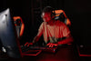 Focused gamer playing online with headset and red lighting environment.