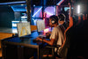 Competitive gaming session with friends indoors featuring high-tech computers and neon lights.
